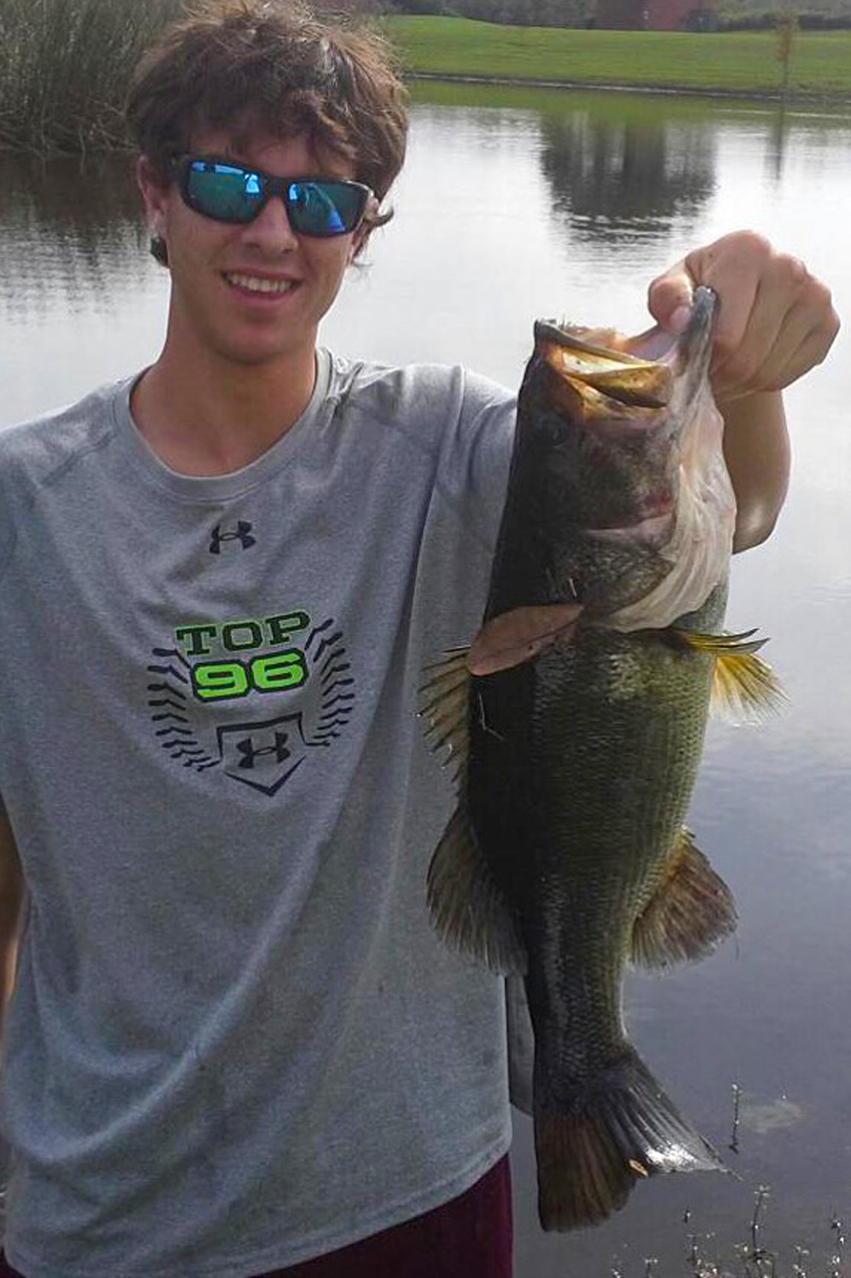 Me holding a largemouth bass by a pond. 